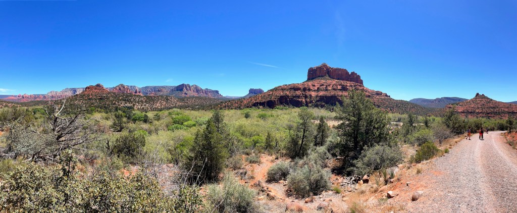 A panoramic view of the Sedona skyline with red rocks and mountains lining the horizon on a beautiful, bright blue and sunny day