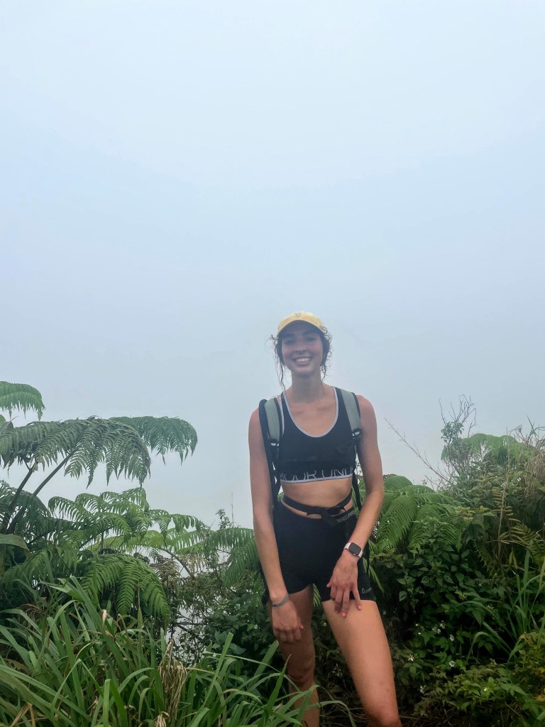 girl standing in front of the cloudy view from the peak of the Waihe'e Ridge Trail
