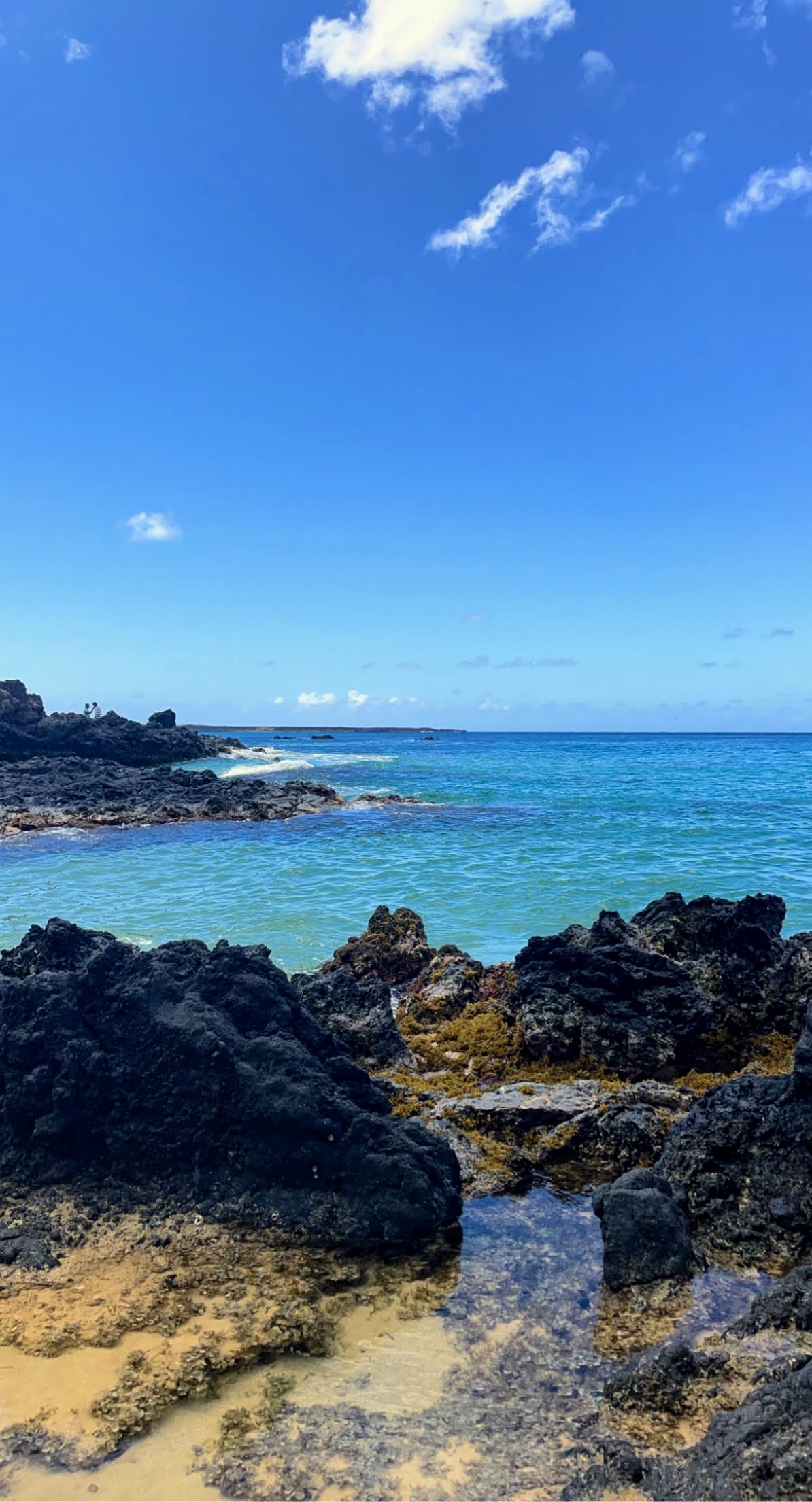 black rocks, tan sand, light blue ocean on maui