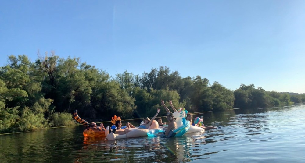 a bunch of friends with their hans in the air floating down the Salt River in Mesa, Arizona on rafts