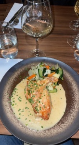 chicken served in a creamy sauce with a side of vegetables and a glass of wine