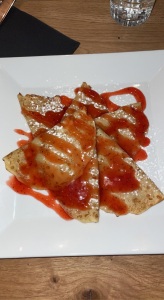 a plate of crêpes serves with a strawberry glaze and powdered sugar