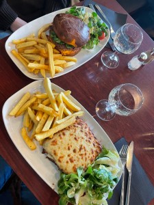 two slices of bread filled with ham and smothered in french cheese, side of fries.