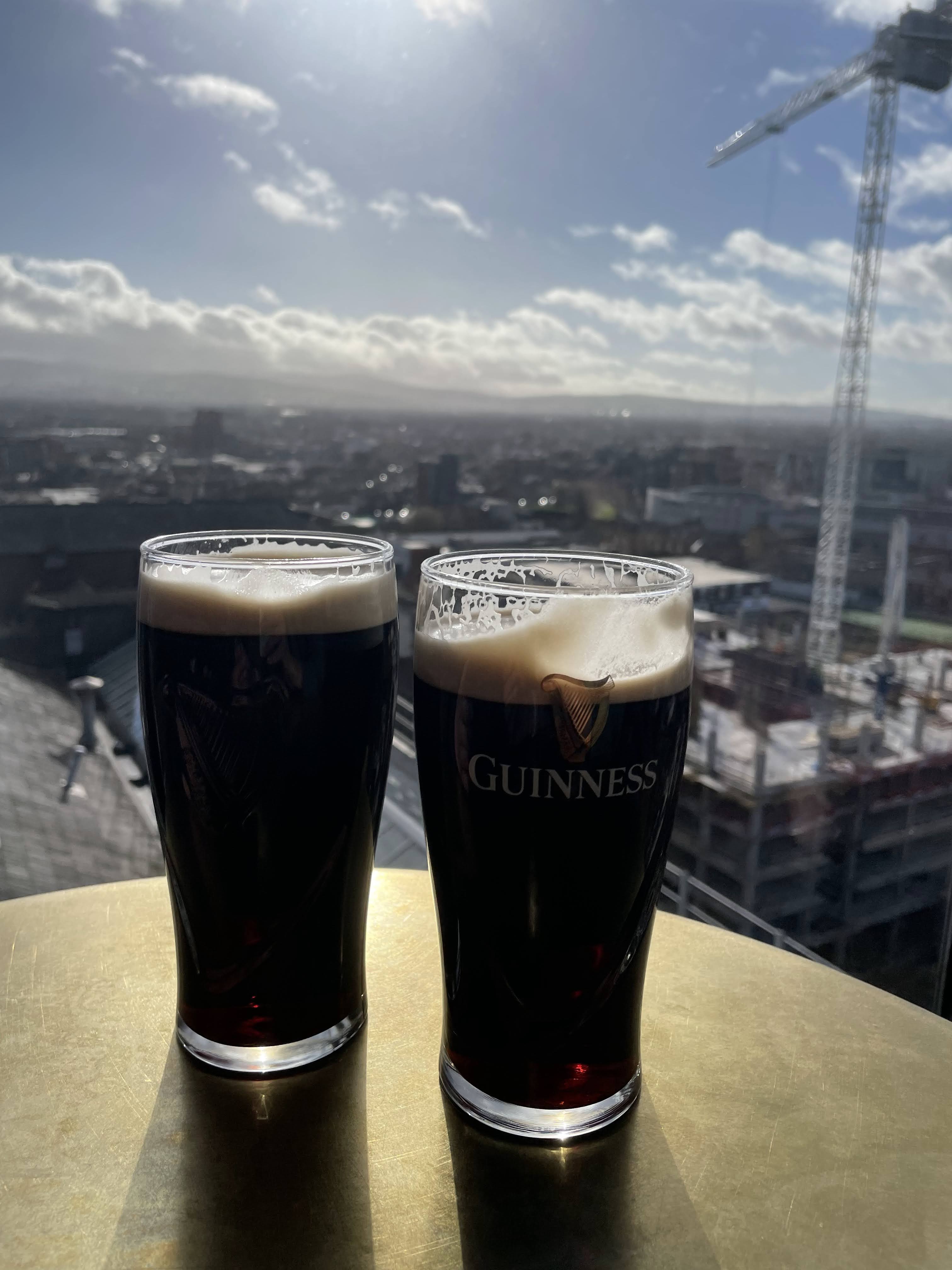 Two pints of Guinness on a table at the top floor of the Guinness Storehouse, with a view of all of Dublin, Ireland