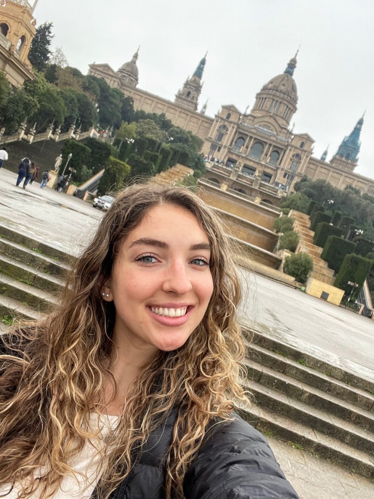A girl taking a selfie at the bottom of the steps of National Palace of Montjuic in Barcelona, Spain