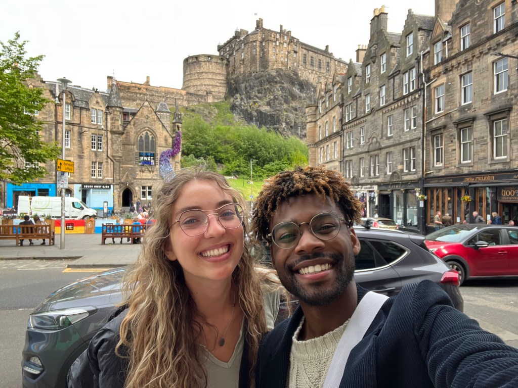 a girl and guy smiling in front of the Edinburgh Castle in Edinburgh, Scotland