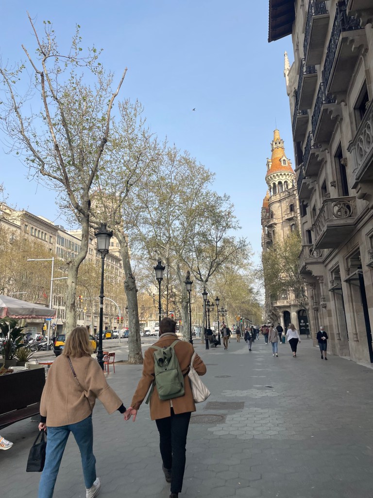 a cute couple holding hands and walking through Barcelona