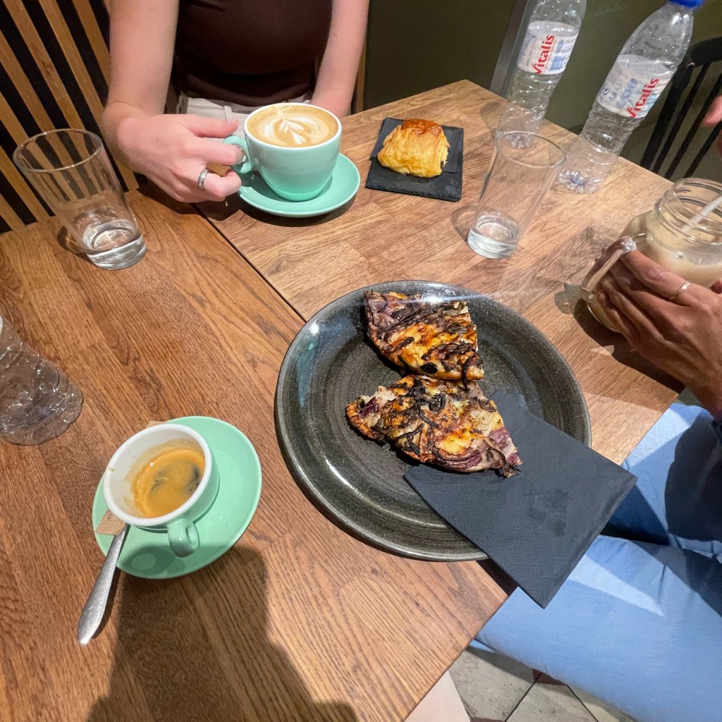 Birds eye view of a table at a cafe with an espresso, latte, pain au chocolat, and two slices of focaccia