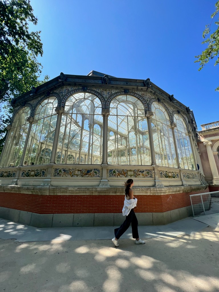 Young woman walking in front of the Glass Palace in El Retiro Park in Madrid, Spain
