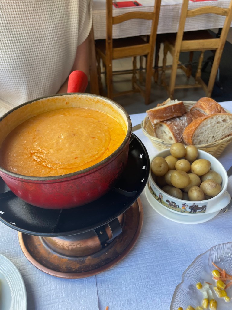 A pot of tomato fondue with a side of mini potatoes and slices of bread, at a classic Swiss restaurant in Geneva, Switzerland