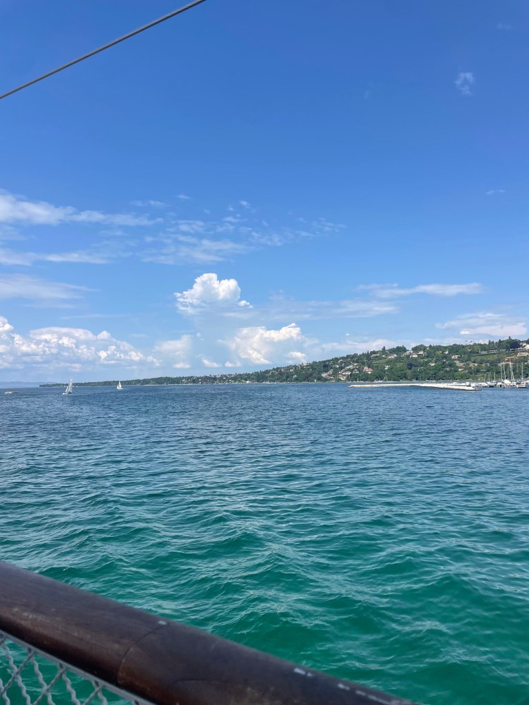 View of the turquoise and gorgeous Lake Geneva from a boat tour with sail boats in the distance
