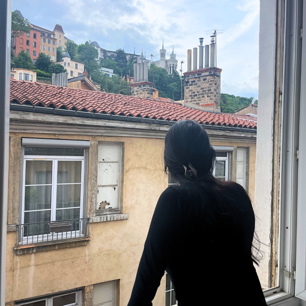 A girl looking out of her Airbnb window with a view of Fourvrière in View Lyon, France