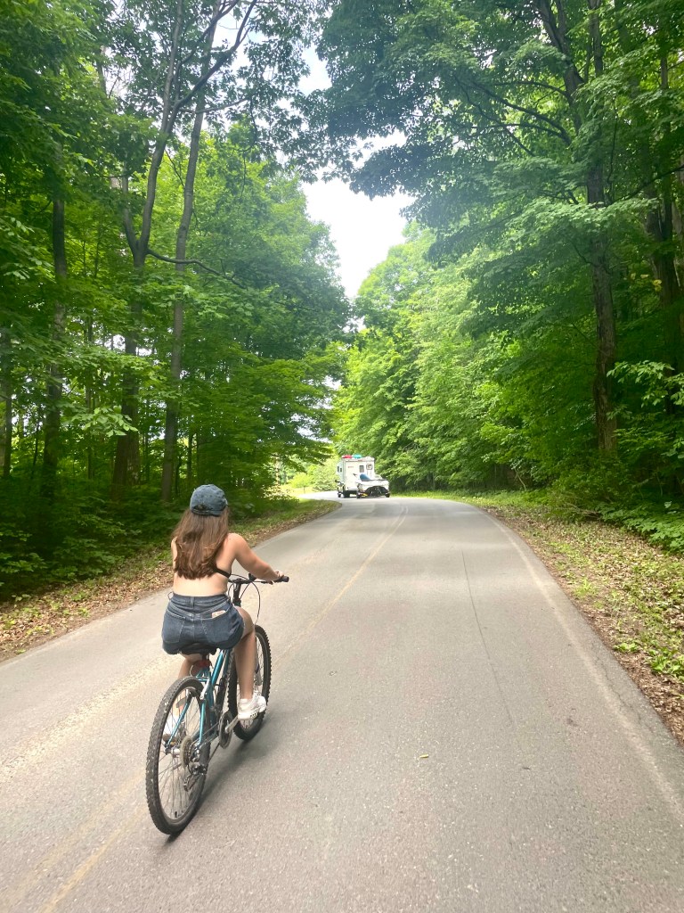 A girl riding a bike through the campgrounds in a bikini top at Wellesley Island in Upstate New York