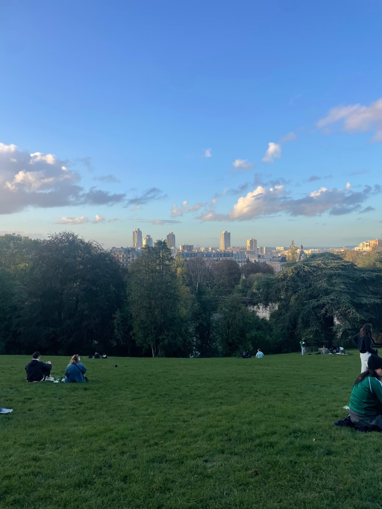 View of the Paris skyline during the sunset from the top of a large hill at Parc des Buttes-Chaumont in the 19th arrondissement