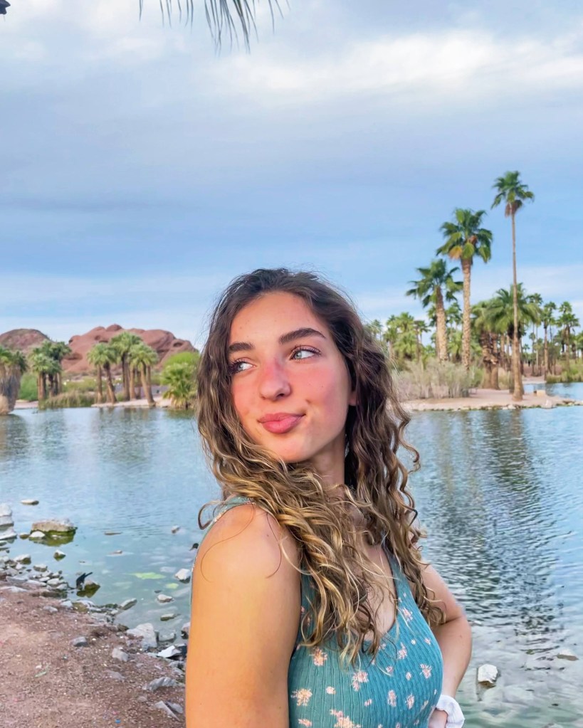 A sun-kissed girl smiling and looking into the distance in front of a pond in Phoenix, Arizona