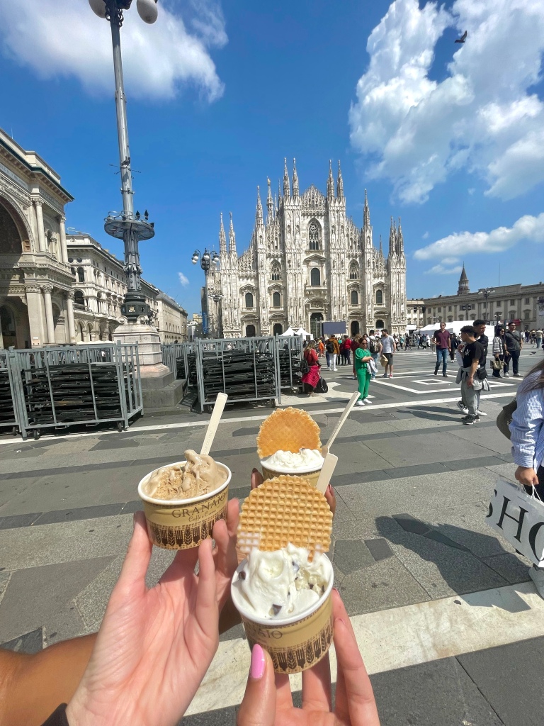 3 friends holding up Italian gelato for a picture in front of the Duomo in Milan, Italy