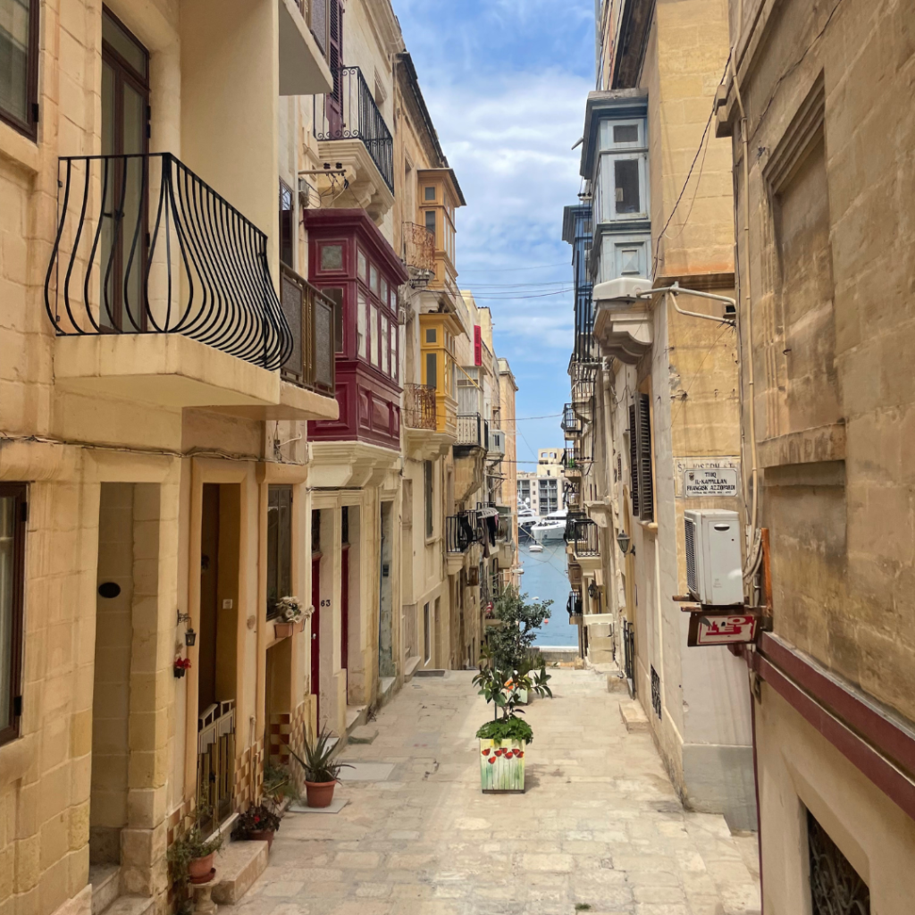 A hidden and beautiful limestone street lined with limestone buildings of the Baroque style leading to the ocean port on the island of Malta