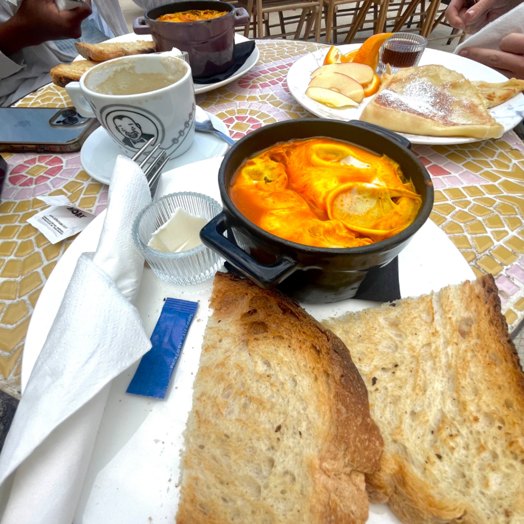 A vibrant bowl of shakshuka with a side of toast and butter at a cute outdoor cafe on the island of Malta in Europe