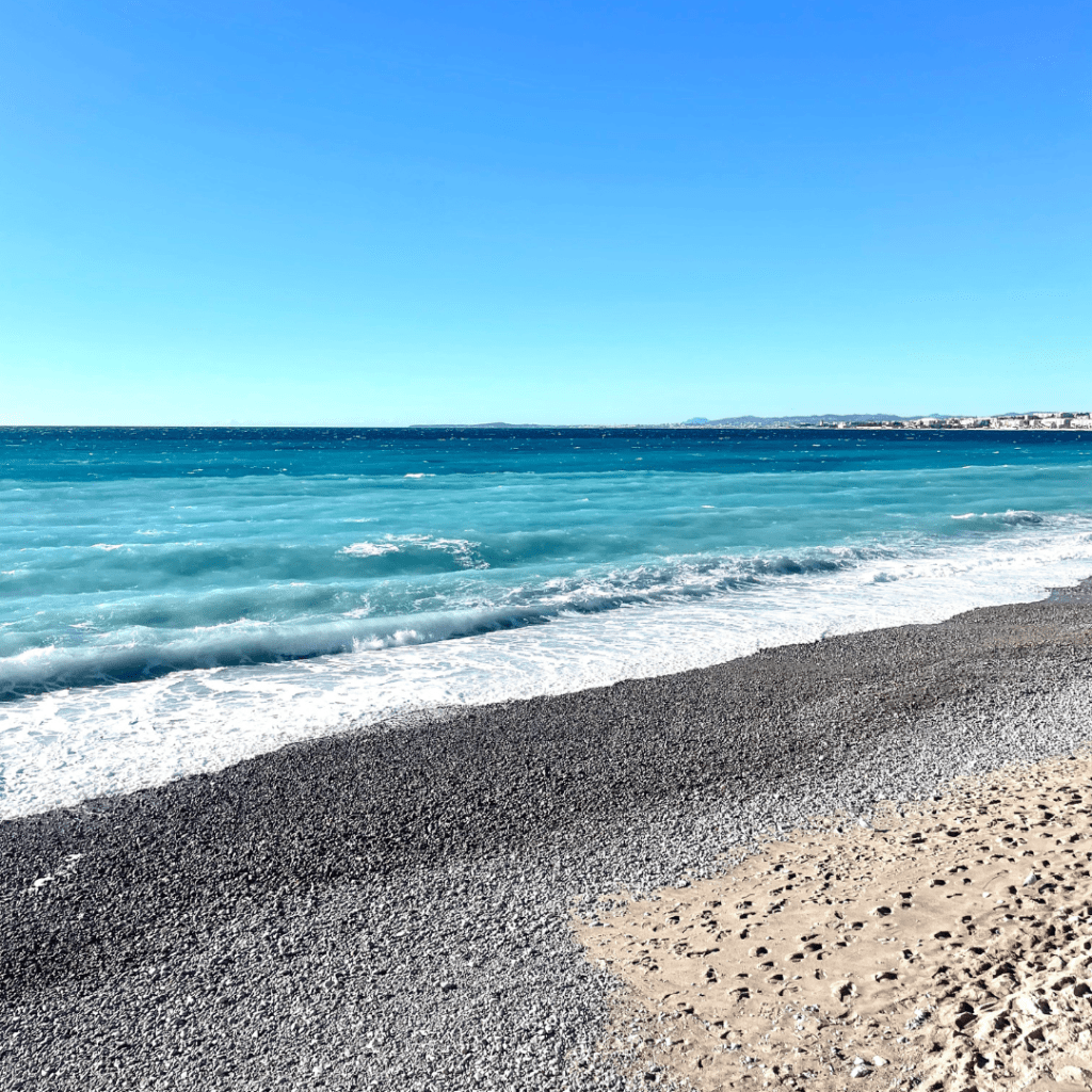 Watching the clear turquoise blue waves break on the shore at Promenade des Anglais in Nice, France, on a clear sunny morning in October.