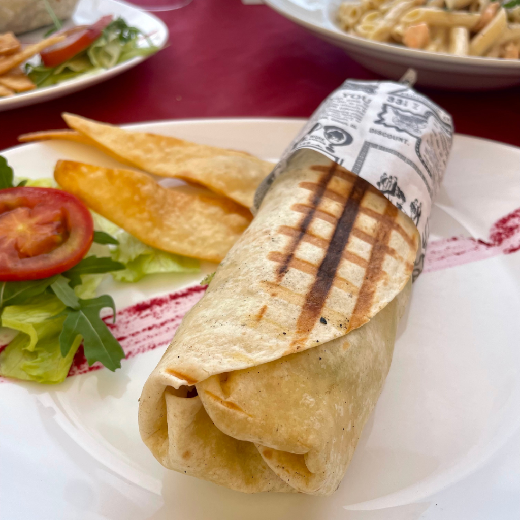 A delicious falafel wrap grilled perfectly, with a side of fresh pita chips at a Mediterranean restaurant on the island of Malta