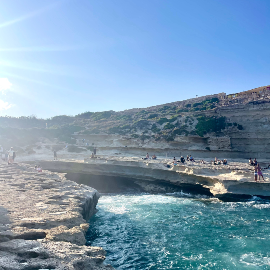 View of the hidden cliff jumping spot from Saint Peter's Pool on the island of Malta