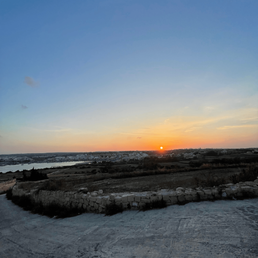 A firery orange sunset setting over vast and empty land on the island of Malta