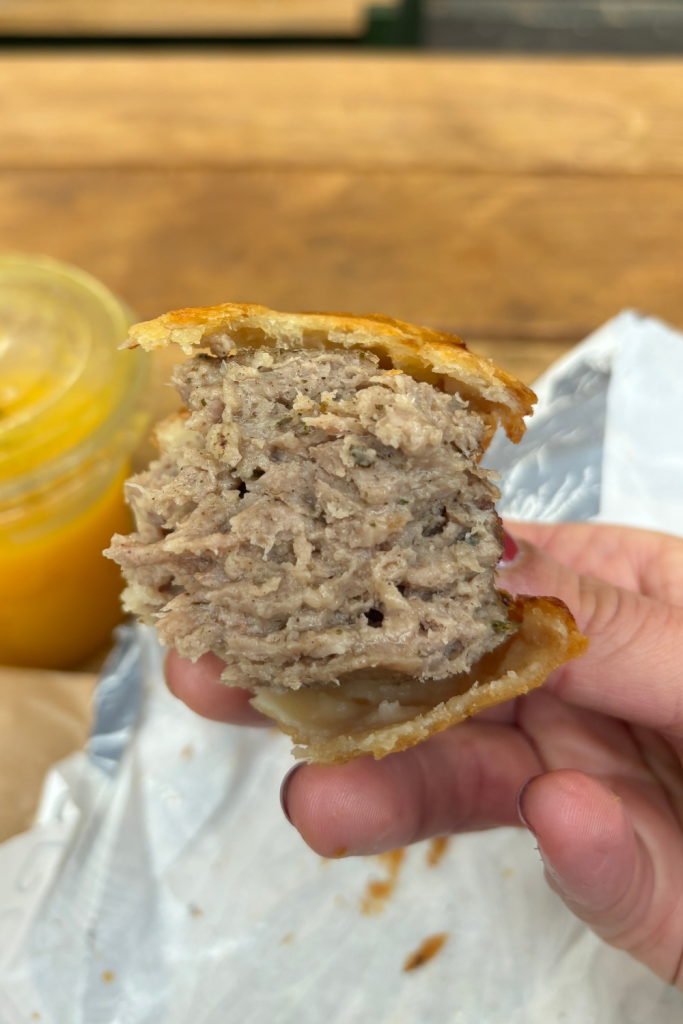 The inside of the famous sausage roll from Borough Market in London, England, with a thick filling of perfectly cooked sausage with a thin layer of a flakey and golden pastry crust on the outside.