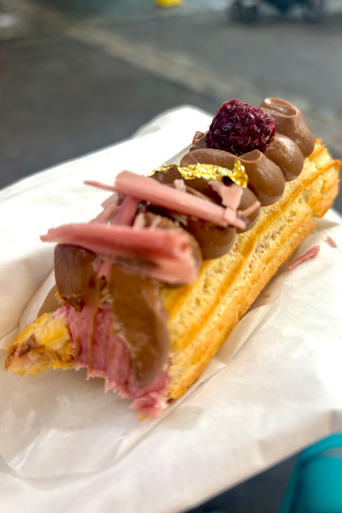 Valentine's Day themed éclair from Borough Market in London, filled with a pink raspberry cream, and topped with a milk chocolate mousse, a golden flake, and a raspberry.