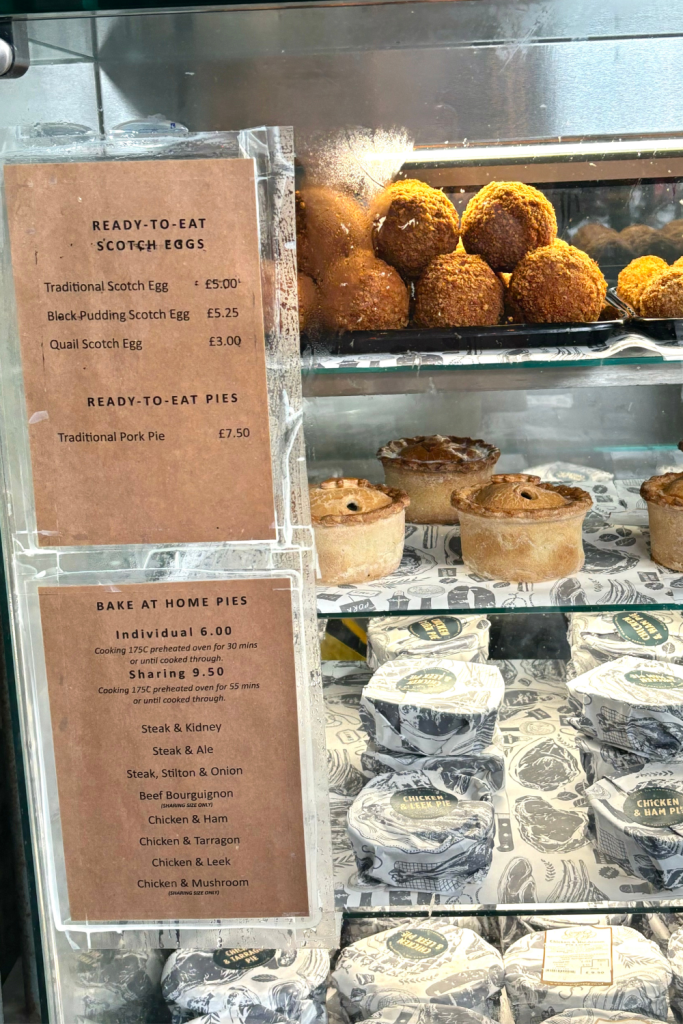 Glass display case at Borough Market in London showing different Scotch Eggs and homemade, ready to eat pies.
