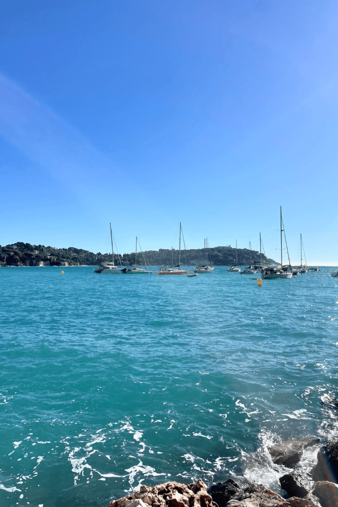 Looking out on the coast of Villefranche sur Mer, France, with gorgeous turquoise blue waters and many fishing boats docked.