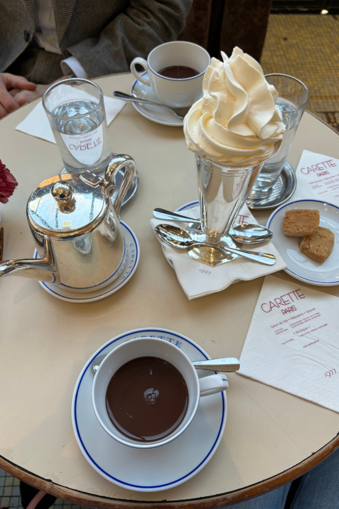 Café aesthetic photo with two mugs of hot chocolate and a tall cone of whipped cream at Carette in Paris