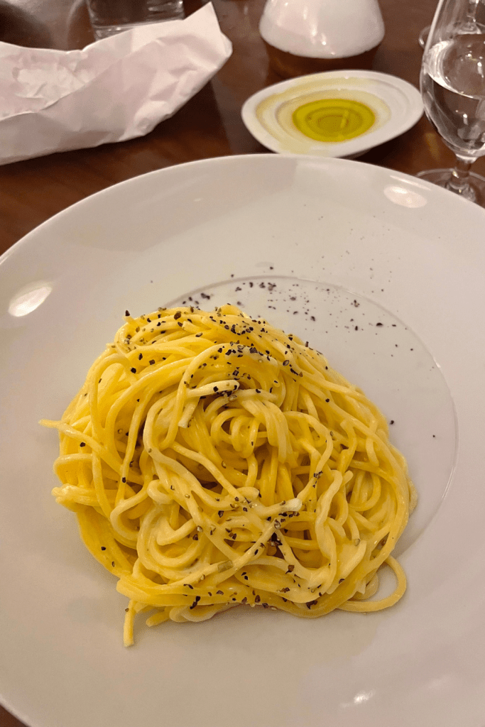 A classic Italian dish, cacio e pepe, plated neatly on a white plate at an Italian restaurant in Nice, France