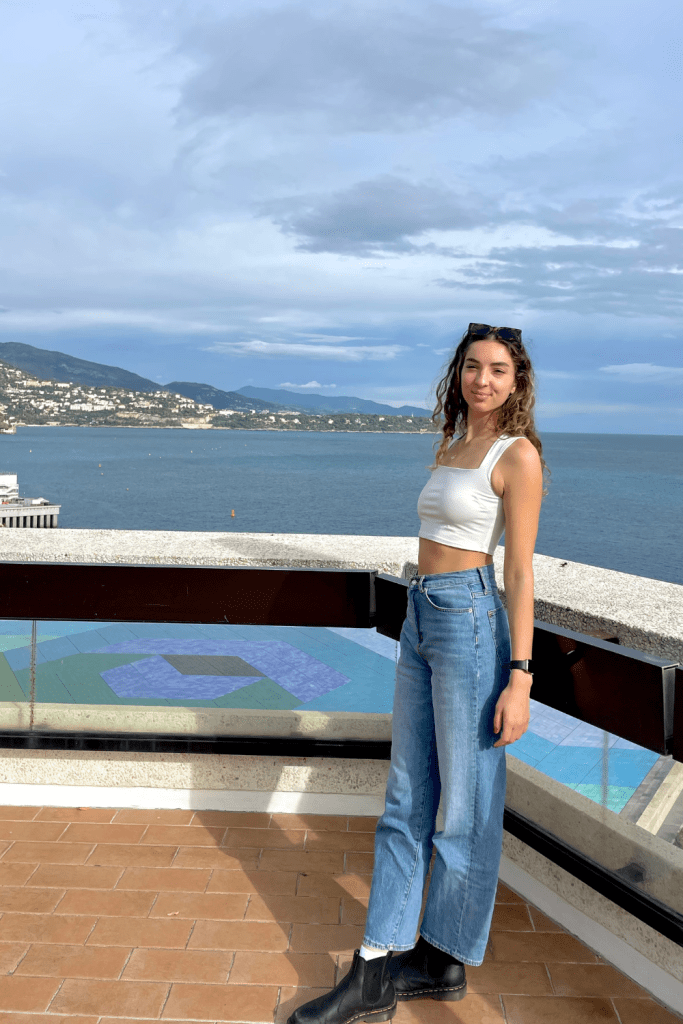 A girl posing in front of the Mediterranean Sea at the marina in Monaco while solo traveling to the south of France