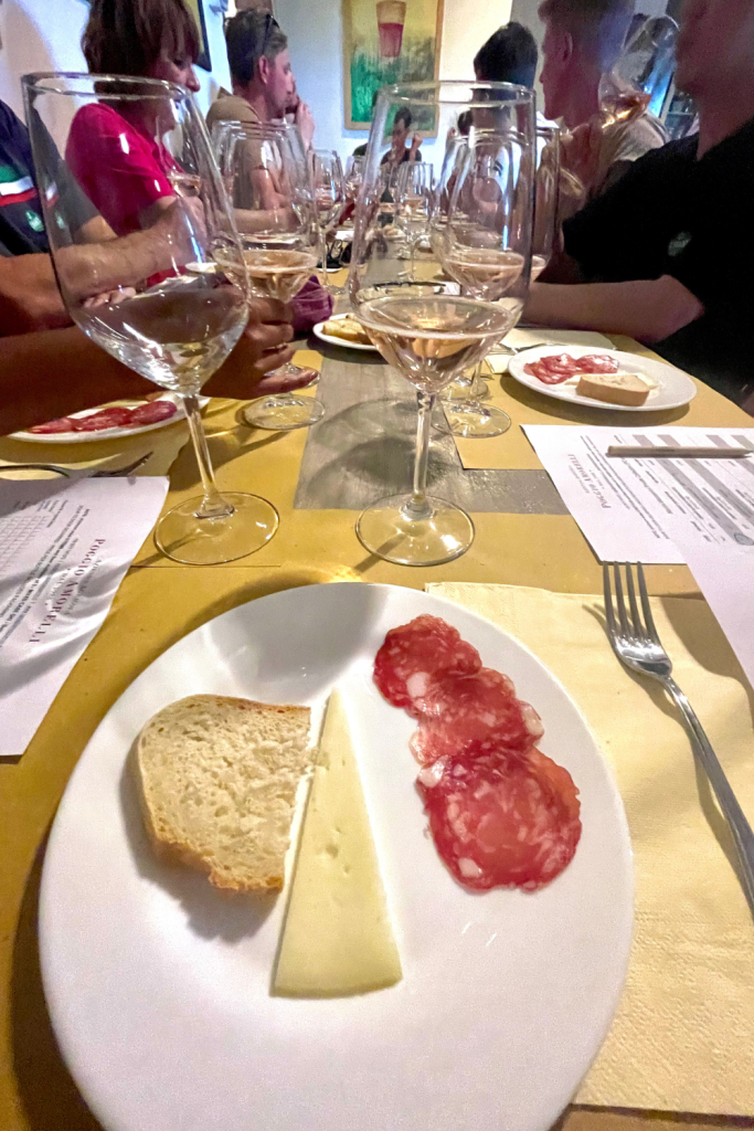 a tasting plate of cheese, bread, and meat, along with wine glasses while on a wine tasting tour in the Tuscany region of Italy