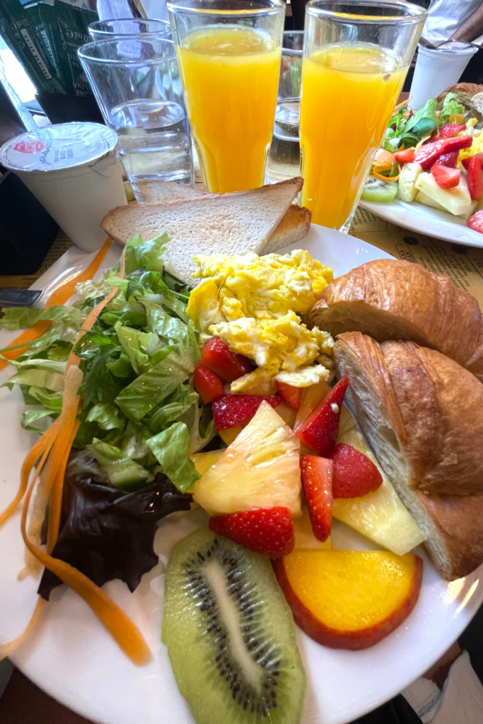 A plate of fresh fruit, scrambled eggs, and a dry croissant from a restaurant in Rome, Italy