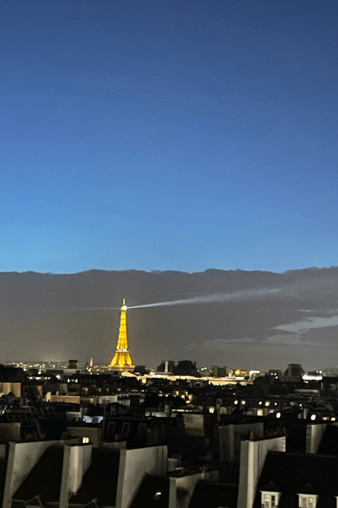 The Eiffel Tower illuminating the Paris skyline during the sunset, from a view above all the apartments at Centre Pompidou.