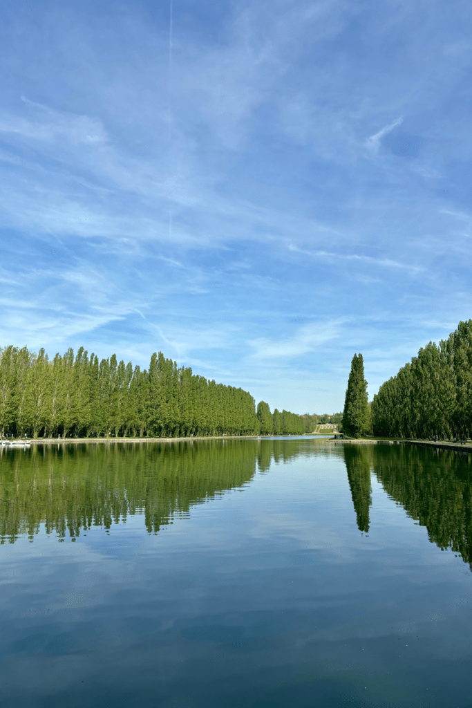 A large, gorgeous pond with tall trees reflecting across the water on a sunny spring day at Parc de Sceaux, south of Paris