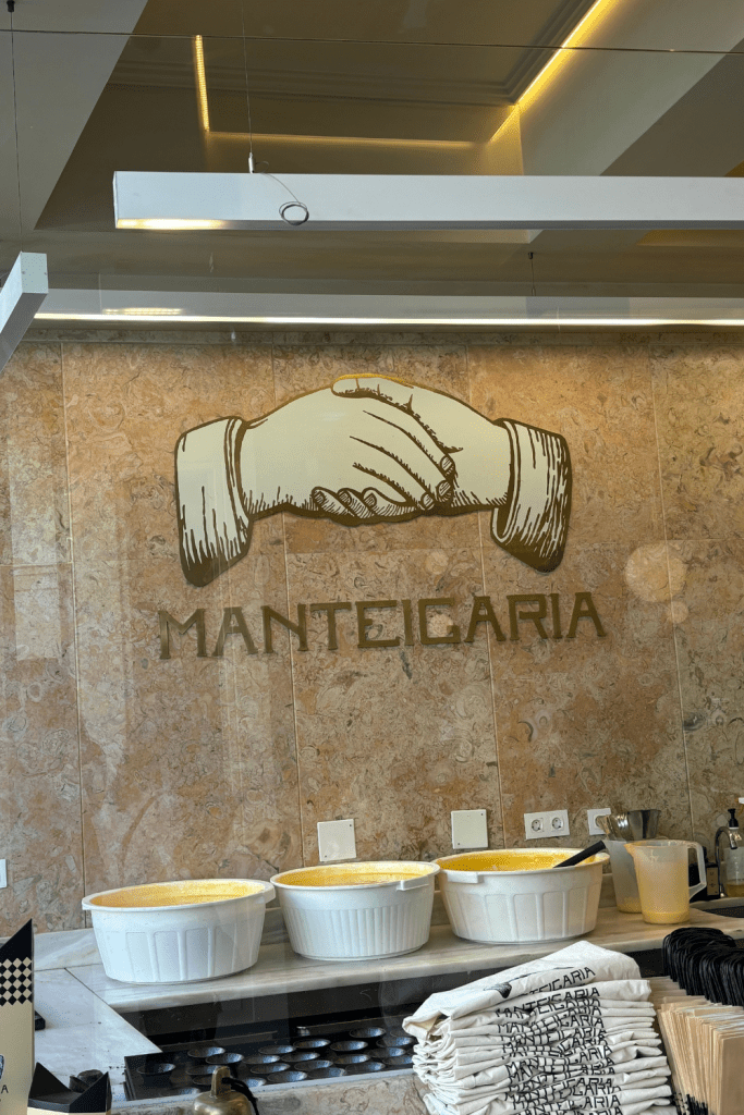 Inside of a pastelaria in Porto, Portugal showing three giant mixing bowls of the custard filling for pastel de natas through a glass window.