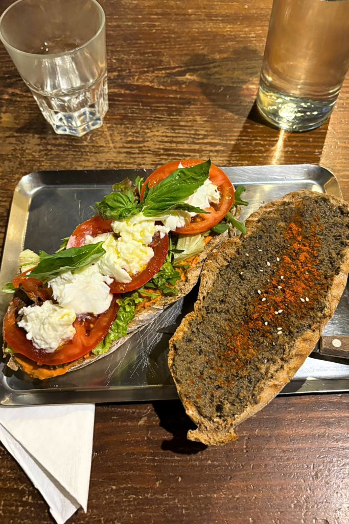 A delicious and fresh sandwich at a family restaurant in Porto, Portugal, made with fresh mozzarella, tomatoes, basil, an olive tapenade, and a homemade sauce and vinaigrette on freshly made bread.
