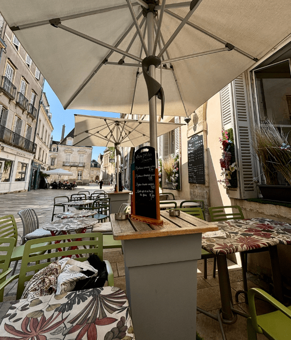 A cozy atmosphere sitting outside on the terrace at a restaurant in Dijon, France, on a warm summer day, under an umbrella for shade
