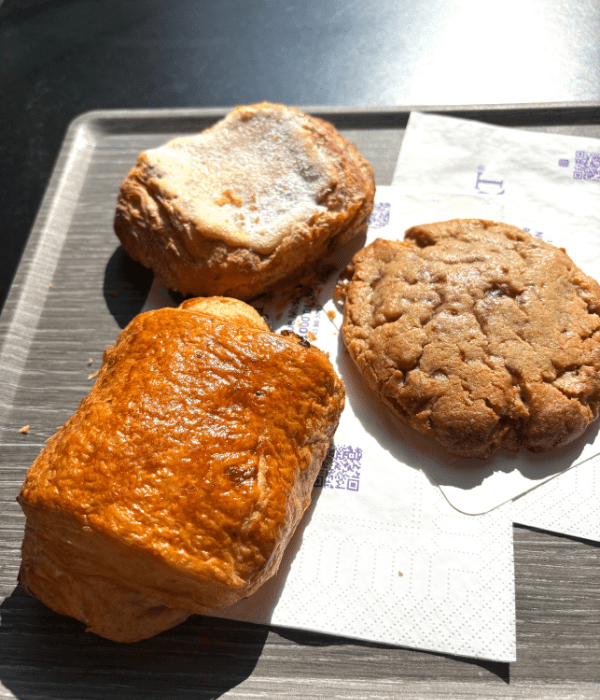 A pain au chocolat, almond pain au chocolat, and a speculoos cookie sitting in the sunlight on a tray from the best boulangerie in Dijon, France.