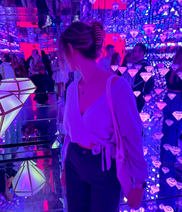 A young traveler walking through a vibrant and immersive, neon purple exhibit at the Moco Museum in Amsterdam, the Netherlands