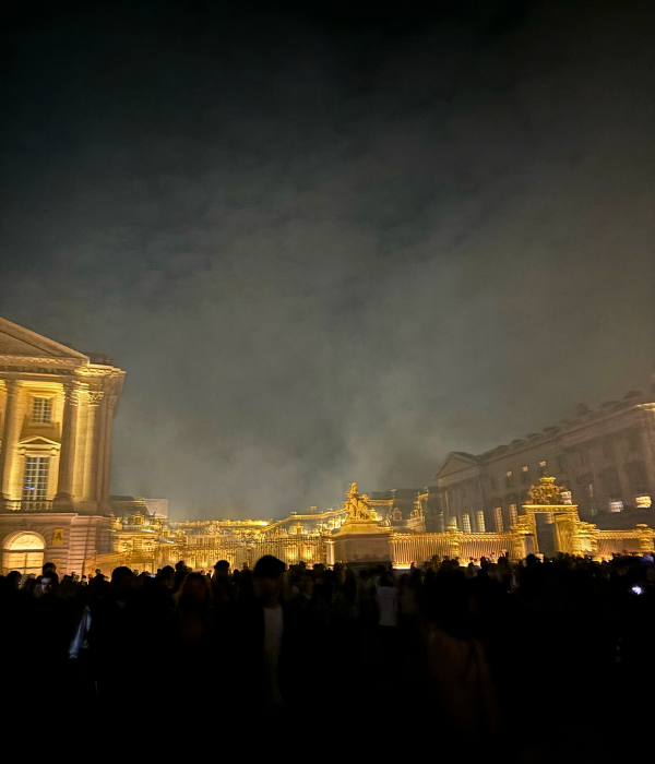 The Château de Versaille lit up in stunning gold lighting at night after an electro music festival in the spring
