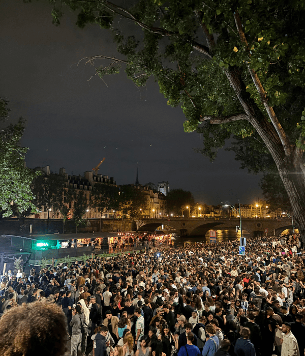 The quai of the Seine in Paris filled with people dancing and celebrating La Fête de Musique at night on the summer solstice in June.