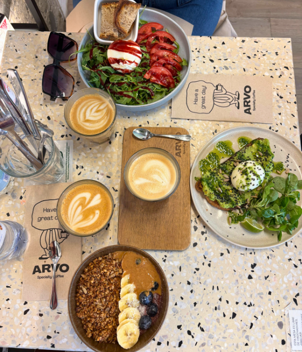 Breakfast at a café in Bilbao, Spain, with an Açai bowl, avocado toast, and burrata salad, with 3 cappuccinos.